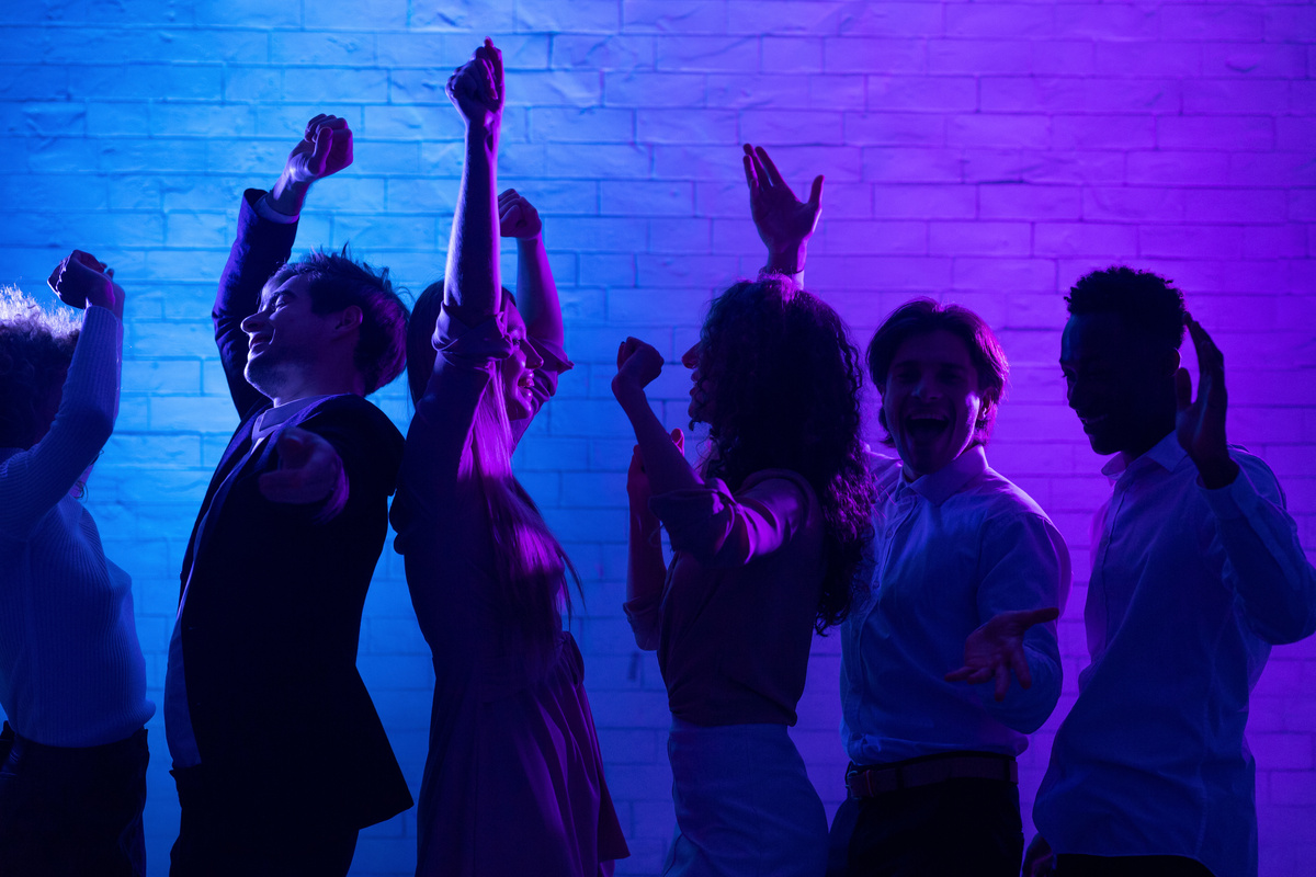 Seis pessoas dançando em um local com luzes azuis 