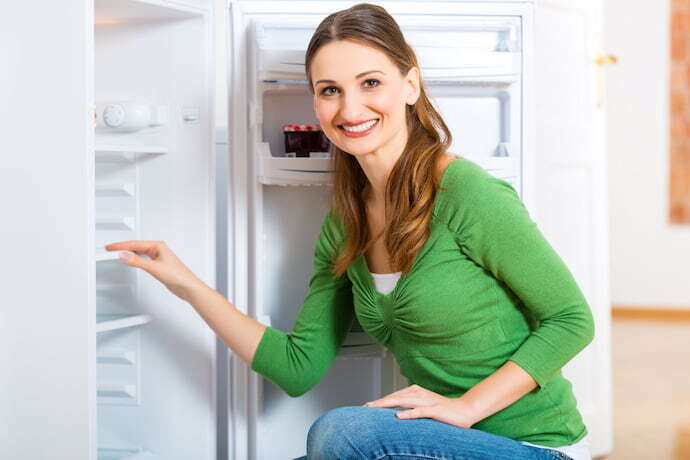 Mulher sorrindo a com a geladeira aberta