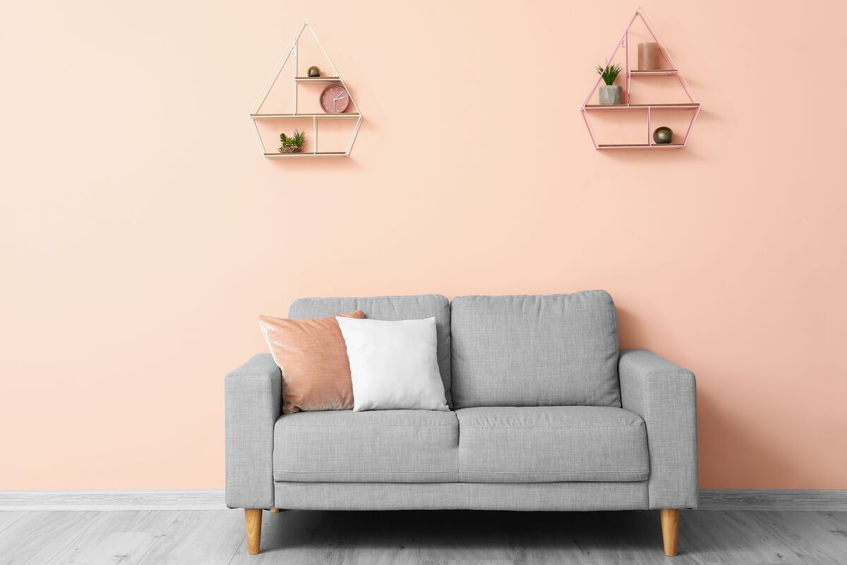 Sofá cinza com almofada cor de rosa combinando com a parede, da mesma cor