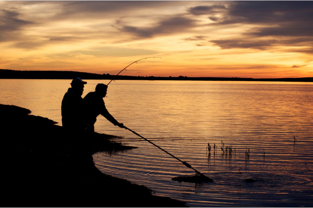 Indivíduos pescando durante o pôr do sol.