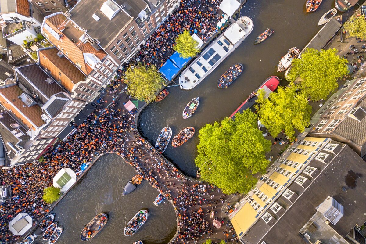 Vista aérea de Amsterdam, nas ruas se veem pessoas de laranja comemorando o Dia do Rei