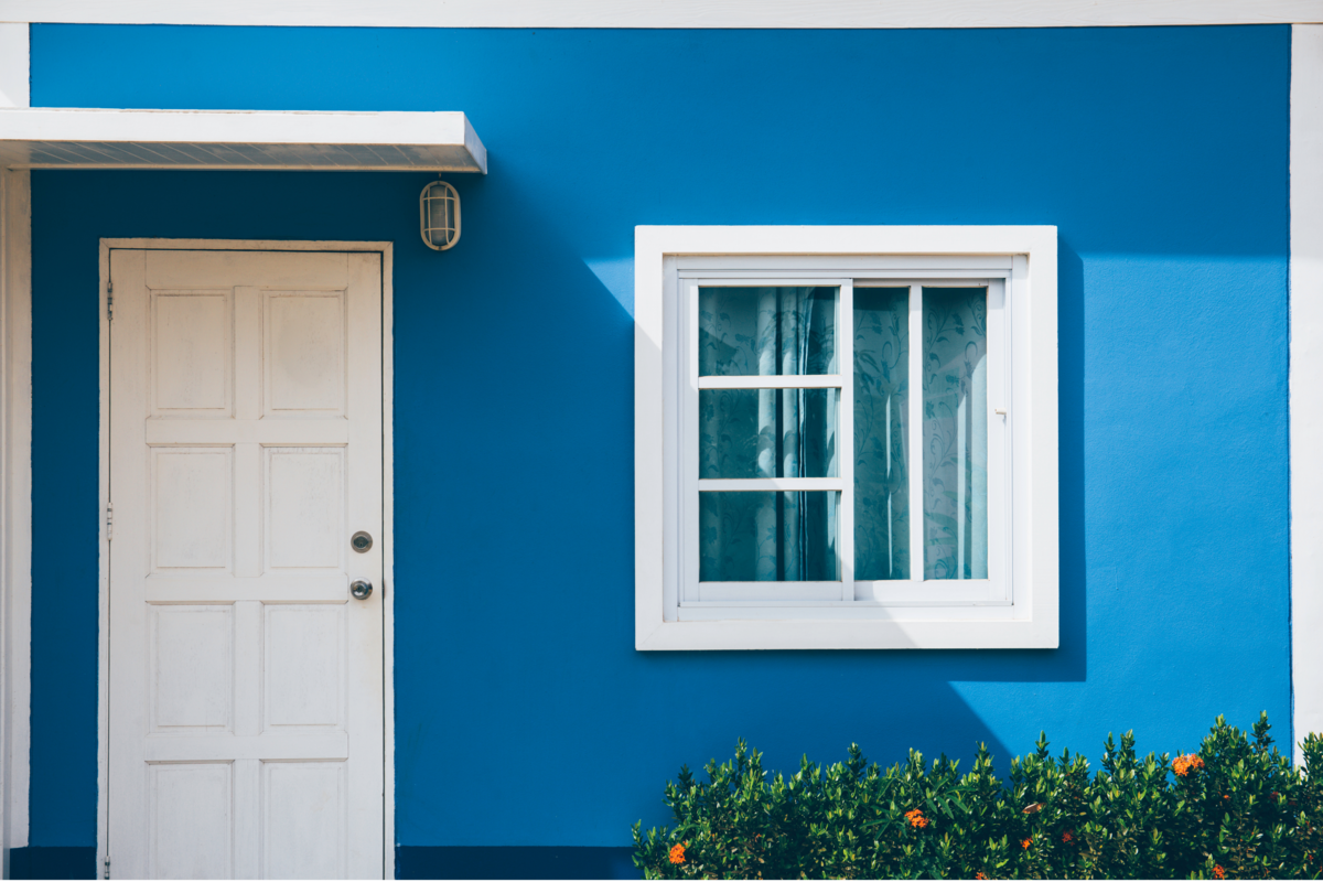 Frente de uma casa com porta e janela sobre fundo azul
