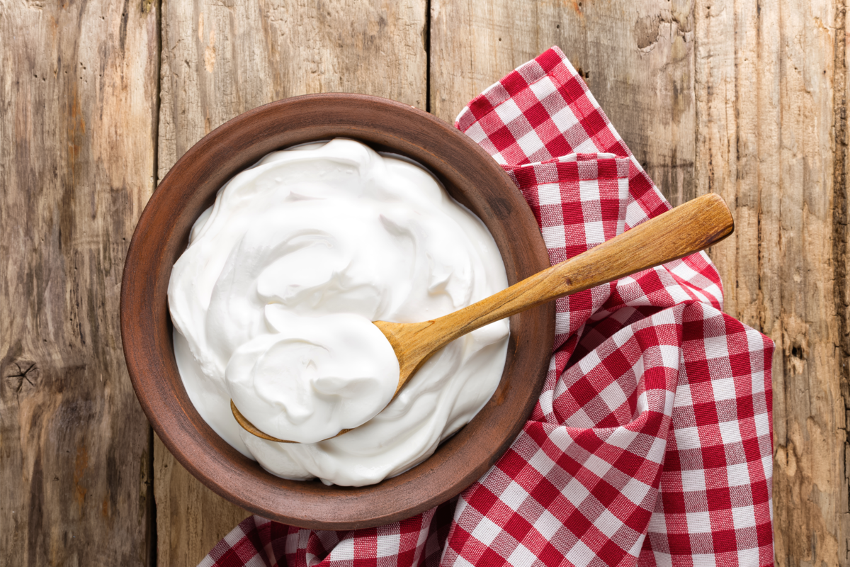 Saboroso iogurte caseiro na tigela na mesa de madeira.