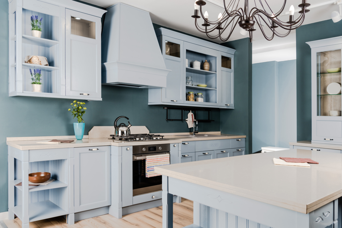 Interior de uma cozinha delicada e leve com móveis de madeira azul claro.