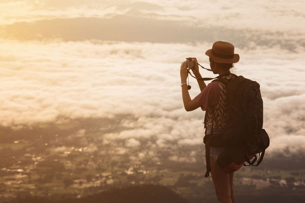 Mulher viajando sozinha no exterior tirando fotos do alto de montanha