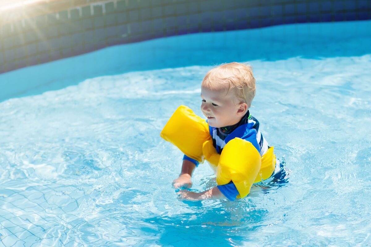 menino se divertindo na piscina com boias
