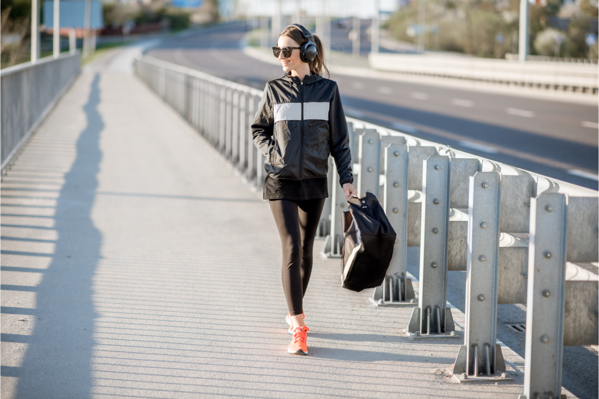 Mulher com roupa de esporte andando após o treinamento 