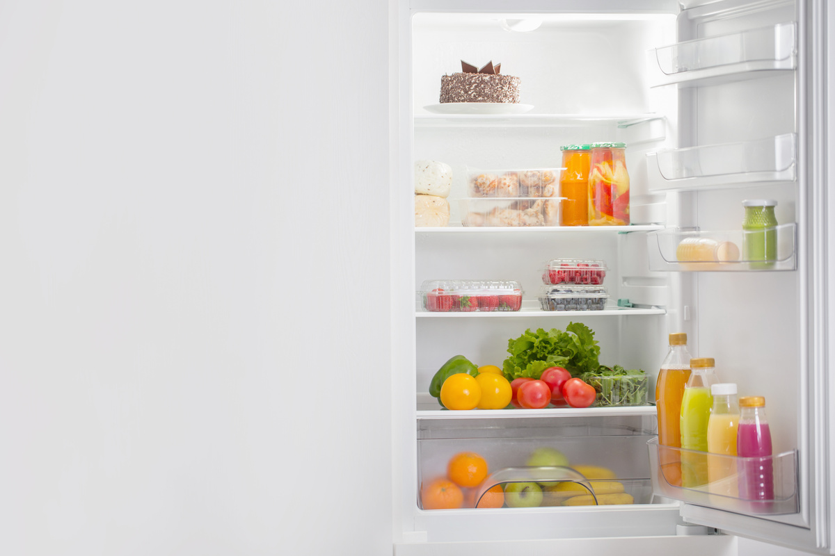Uma geladeira aberta e com comida dentro