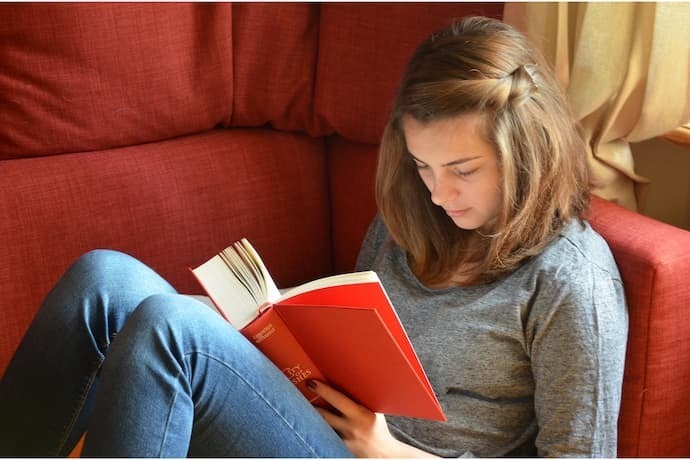 Garota lendo livro sentada no sofá