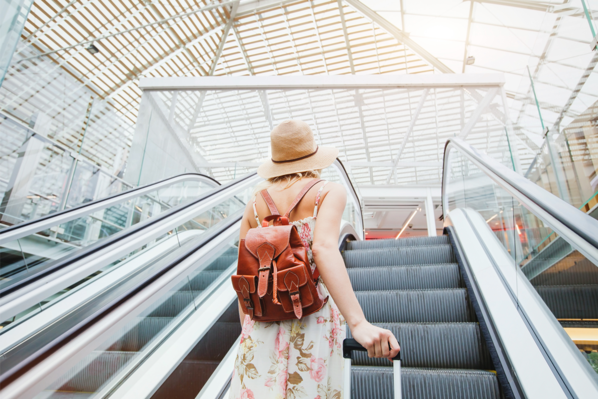 Mulher viajando com mochila em uma escada rolante