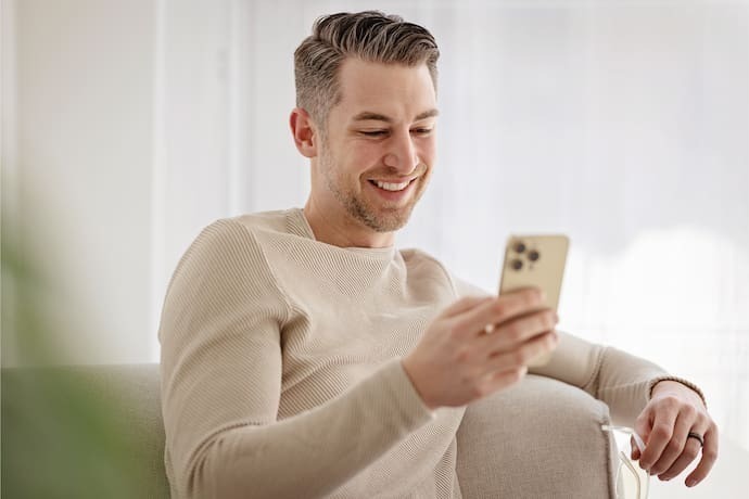 Homem sorrindo enquanto manuseia seu celular