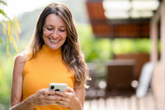 Mulher sorrindo enquanto olha para seu celular