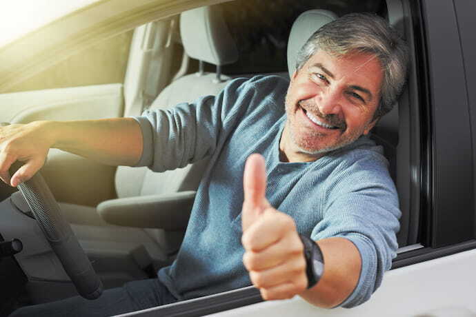 Homem sorrindo dentro de seu carro