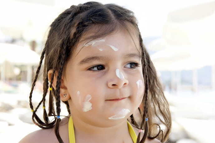 Criança com o rosto cheio de protetor solar