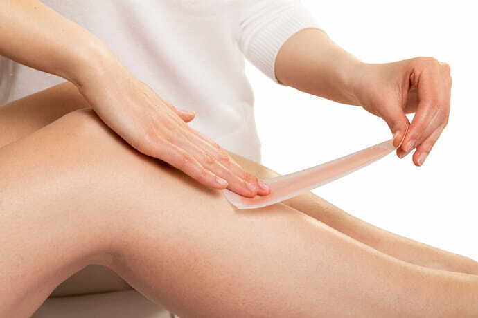 Pessoa depilando perna feminina