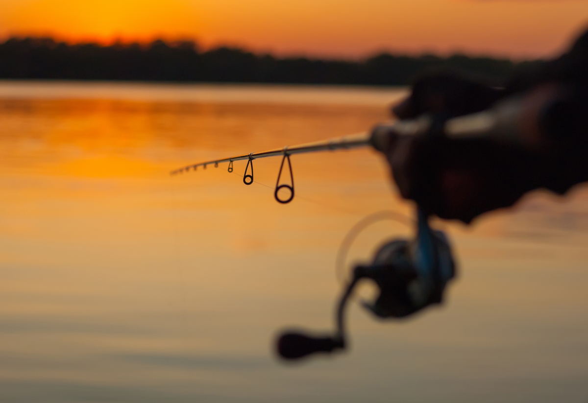 Vara de pesca em rio durante o pôr do sol