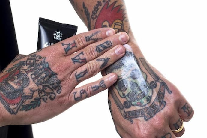 Homem passando hidratante na tatuagem da mão