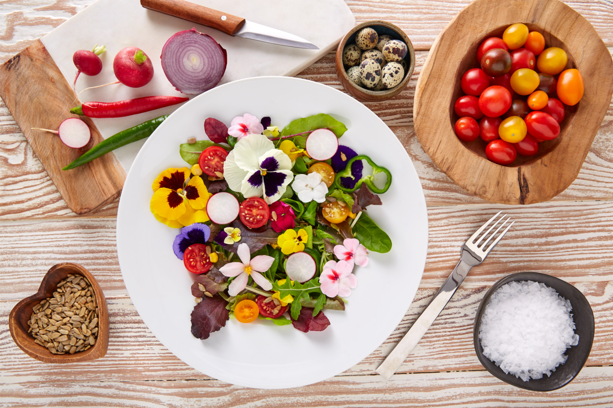 Salada de flores comestíveis e com outros ingredientes ao lado.