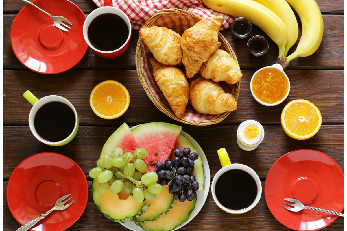 Café da manhã  com croissant e frutas em uma mesa de madeira