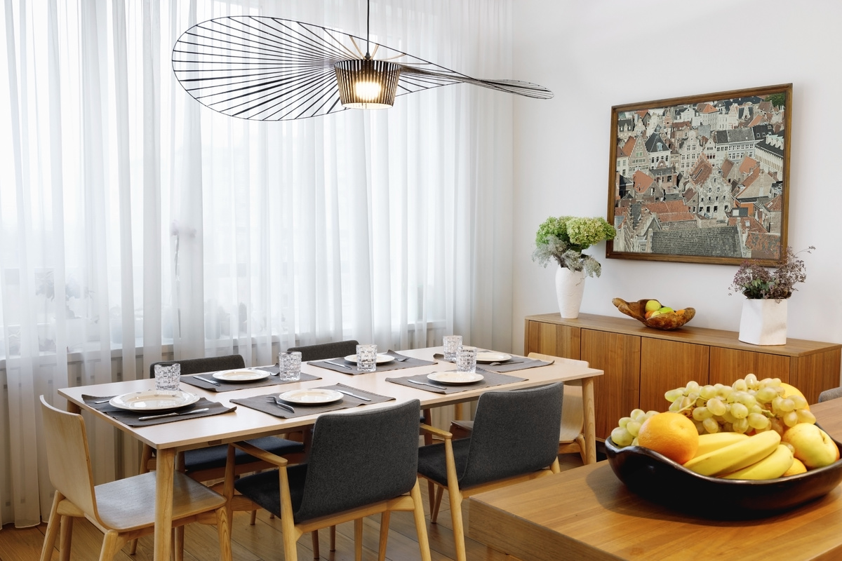 Uma sala de jantar com cadeiras pretas, mesa marrom e pratos sobre a mesa