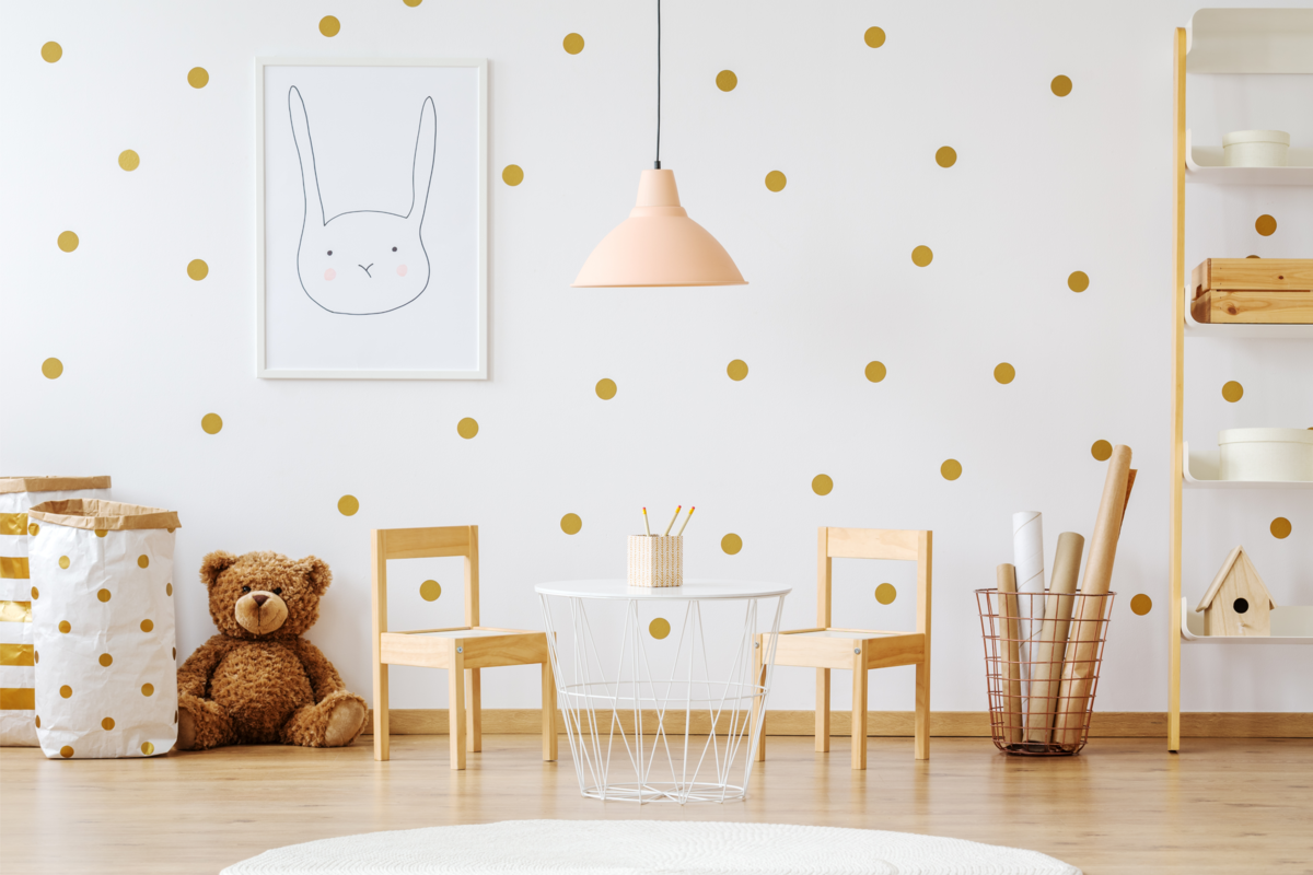 Quarto infantil com parede branca com bolas marrons, móveis e um urso de pelúcia