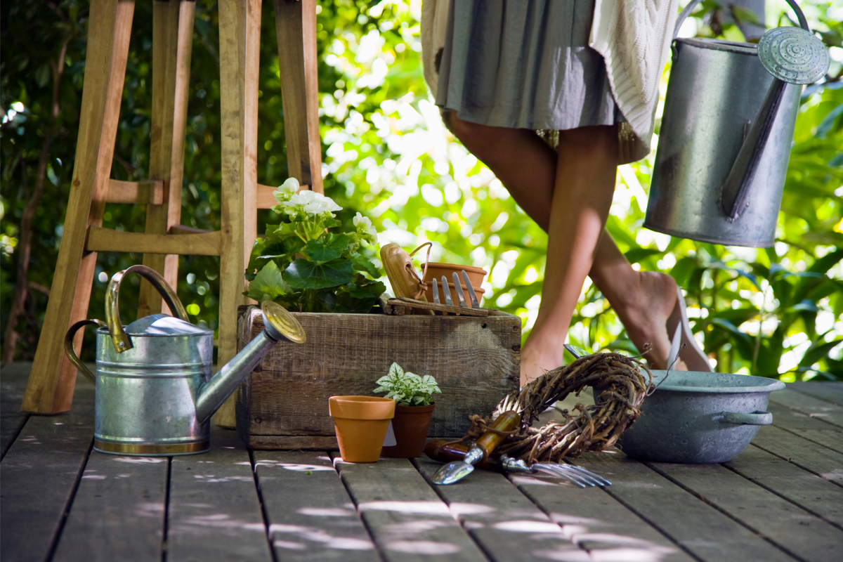 Pernas de uma mulher próxima as ferramentas de jardinagem