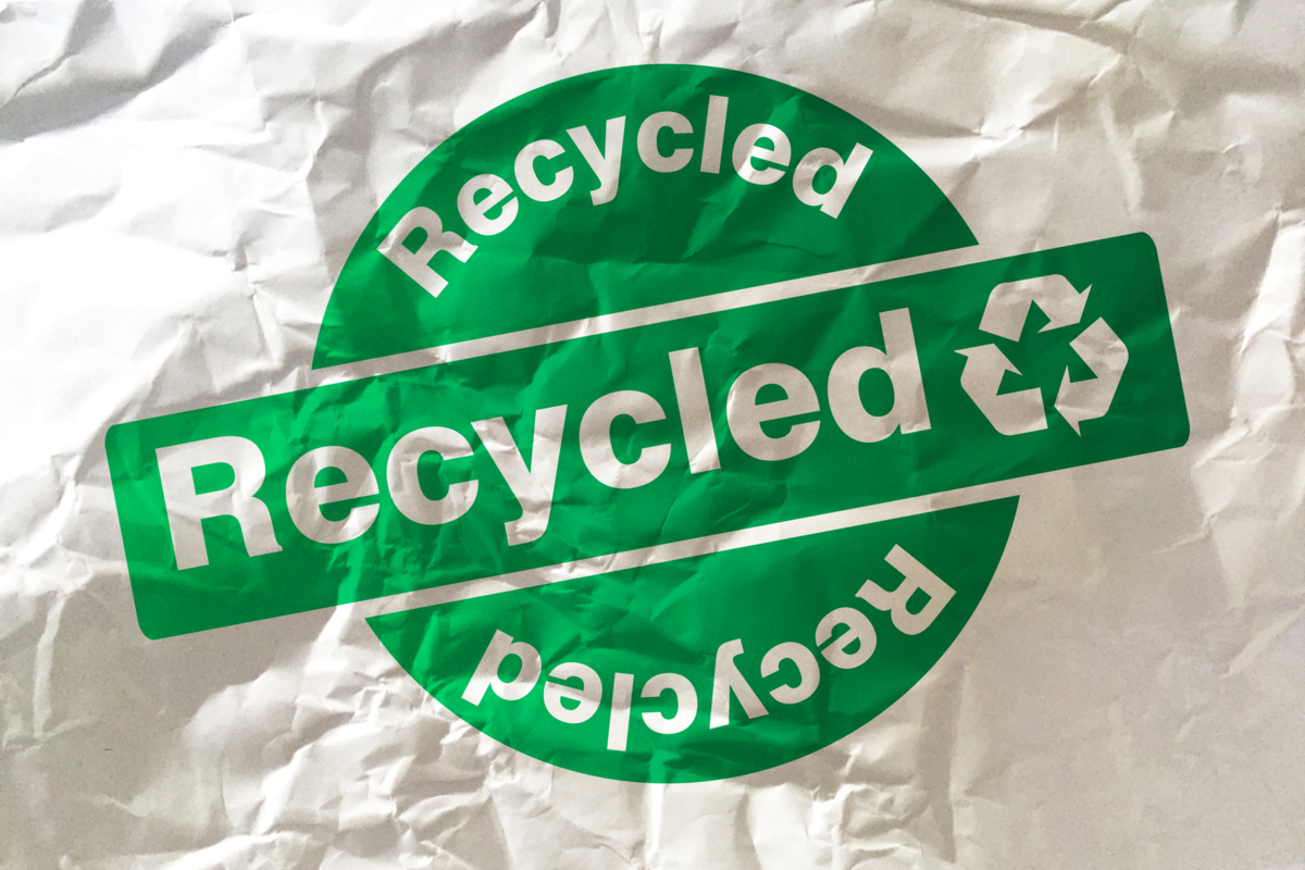 Papel amassado com o símbolo verde da reciclagem.