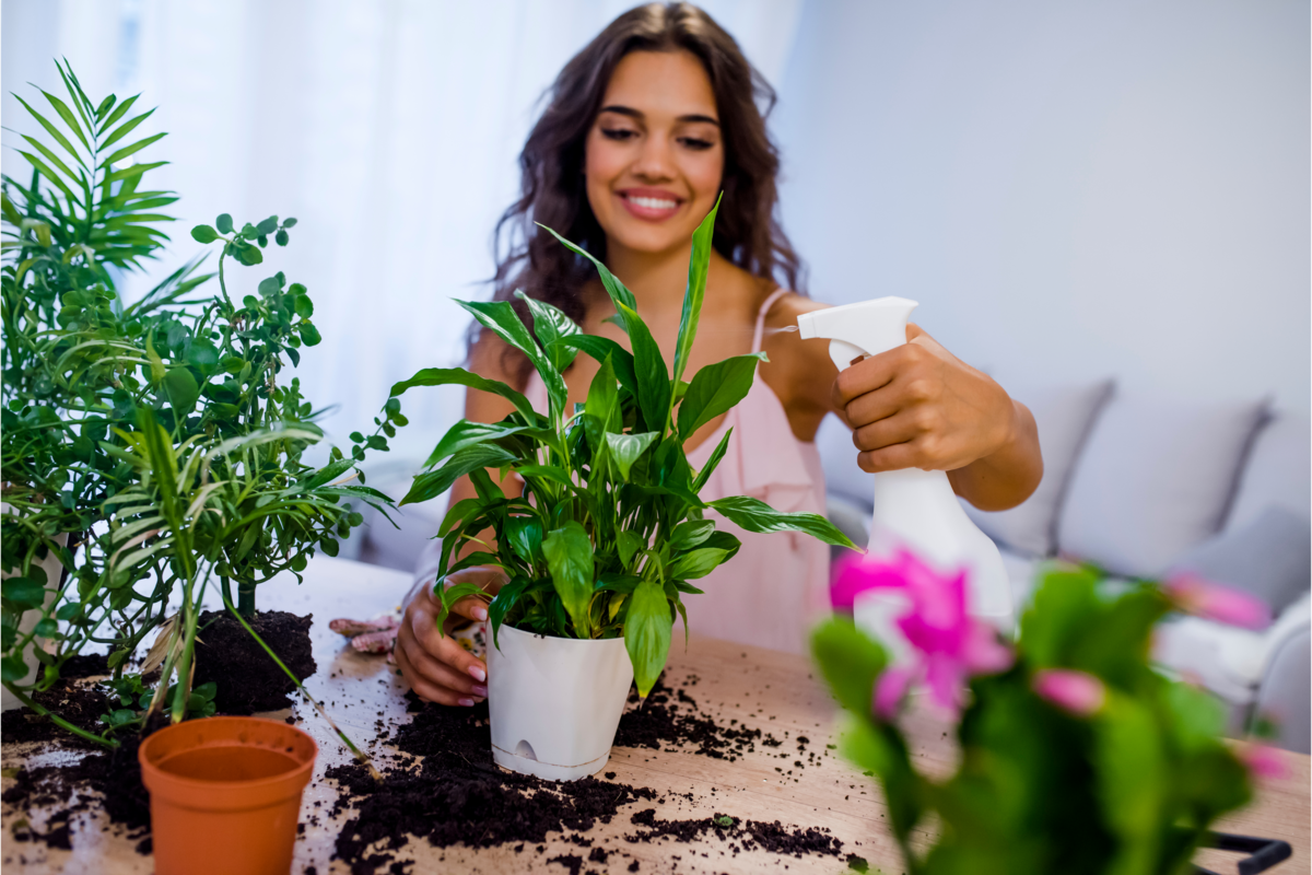 Mulher sorrindo e cuidando das plantas dentro de casa.
