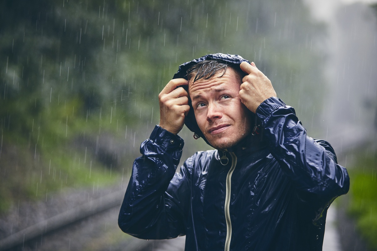 Um homem na chuva usando roupa de chuva
