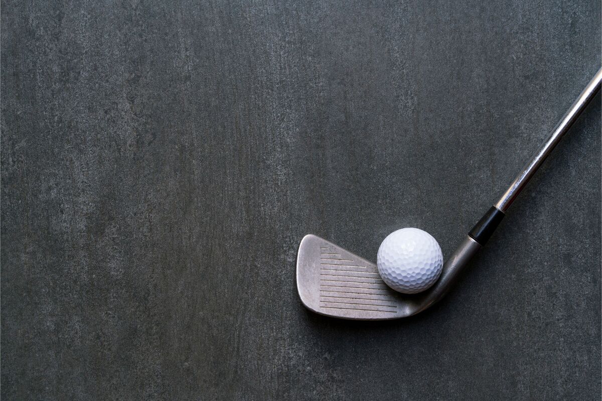 Bola de golfe e taco de golfe em fundo cinza