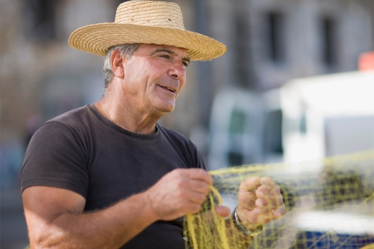 Homem de chapéu preparando a rede de pesca.