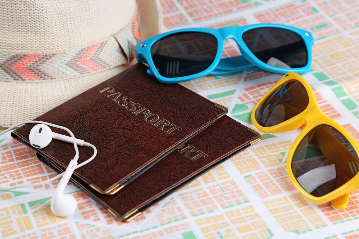 Passaportes, óculos de sol e fone de ouvido em cima de mesa