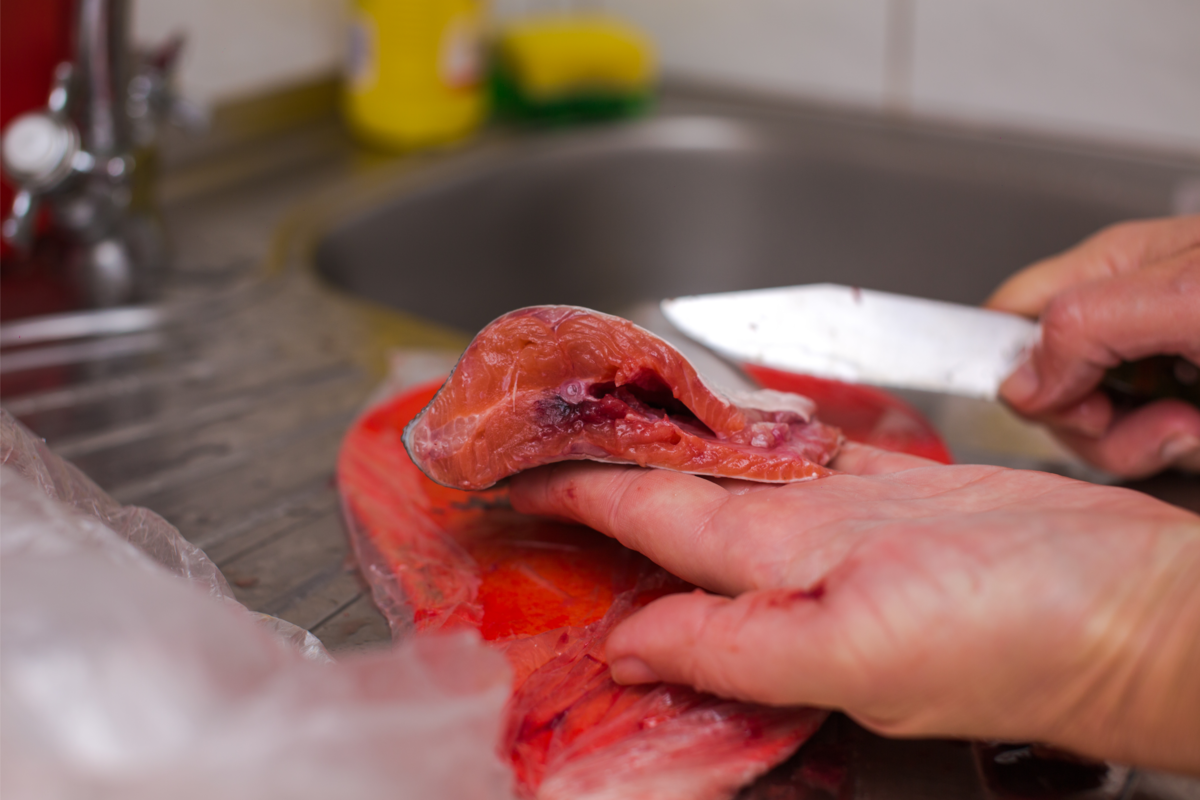 Uma mulher com uma faca e limpando o peixe porco