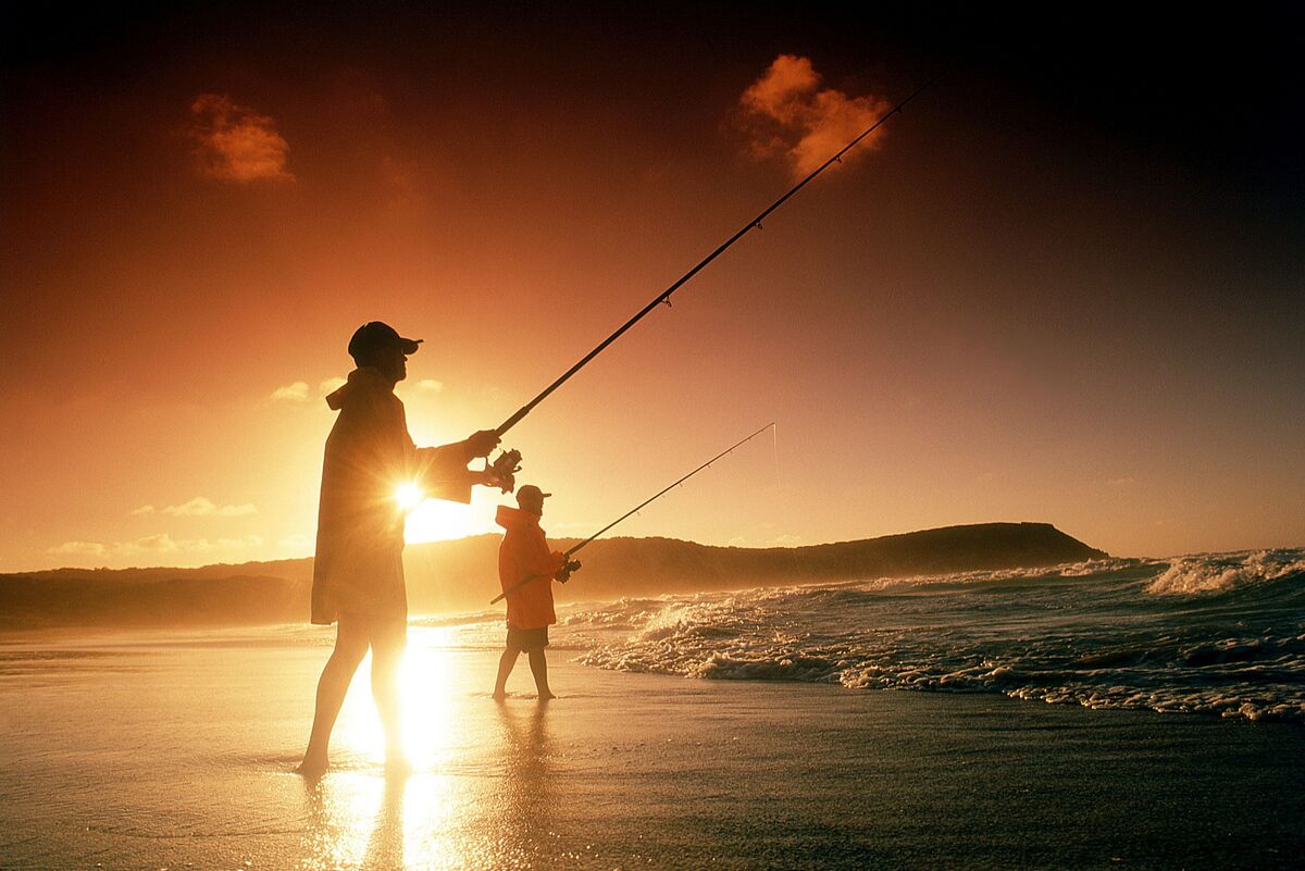 Duas pessoas pescando na praia 