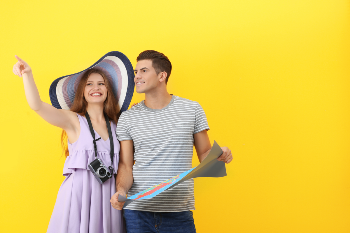 Dois turistas sorridentes com um mapa e uma câmera.