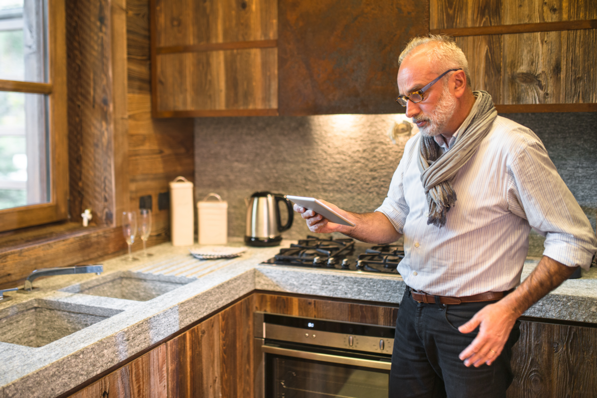 Homem usando o tablet na cozinha moderna.