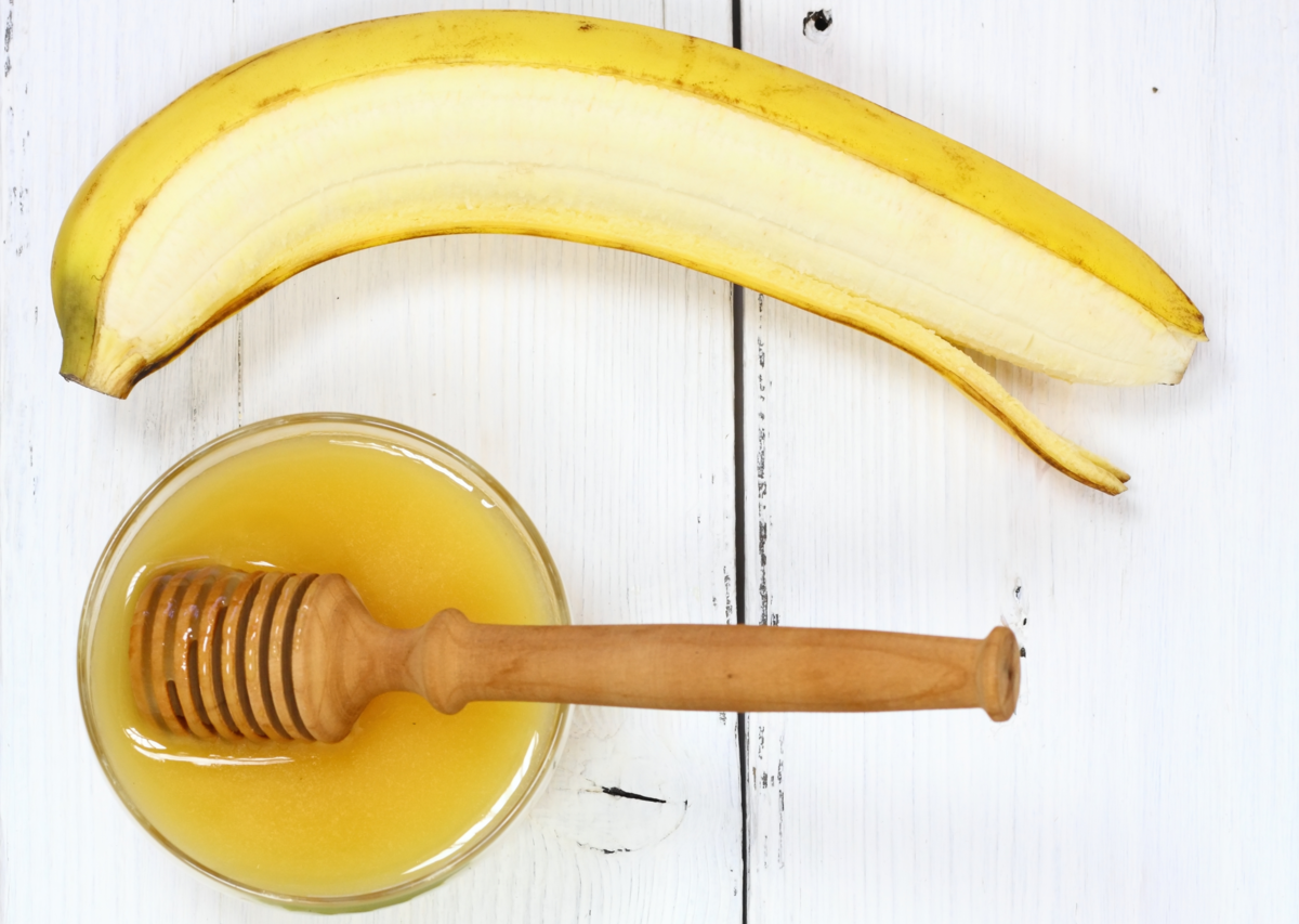 Banana com parte descascada e pote de mel