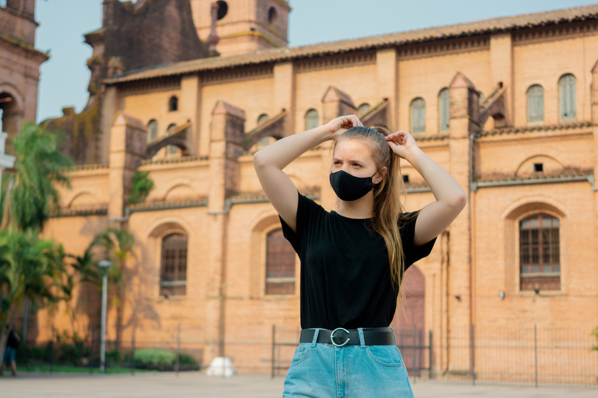 Menina de máscara e atrás dela a Catedral Basílica de São Lourenço