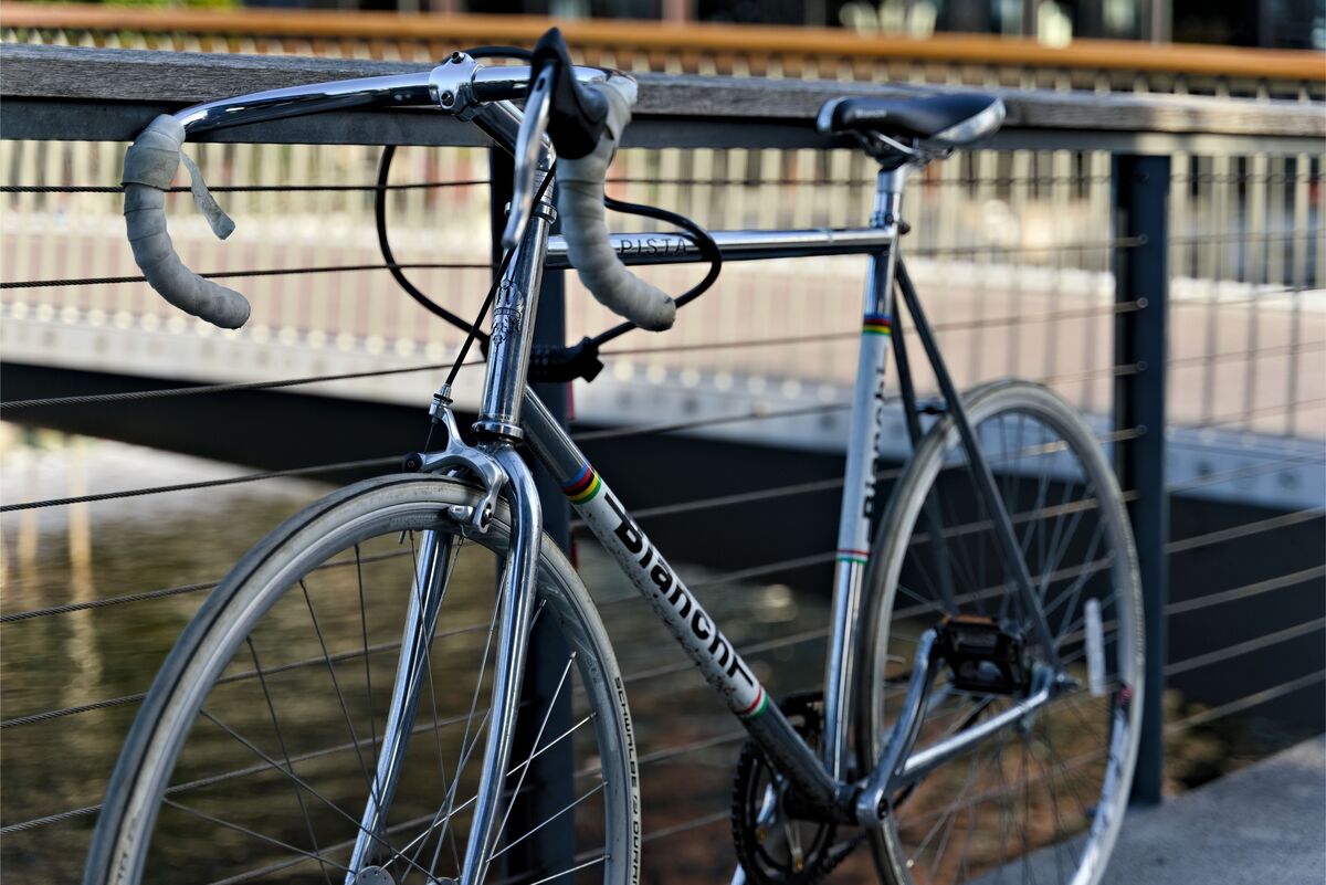Bicicleta prata encostada em grade 