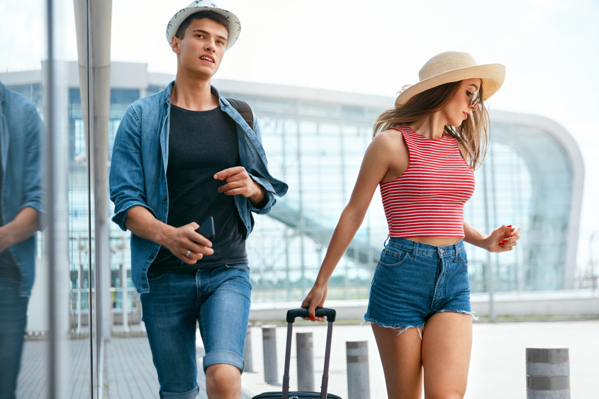 Um casal de turistas com a mulher levando uma mala 