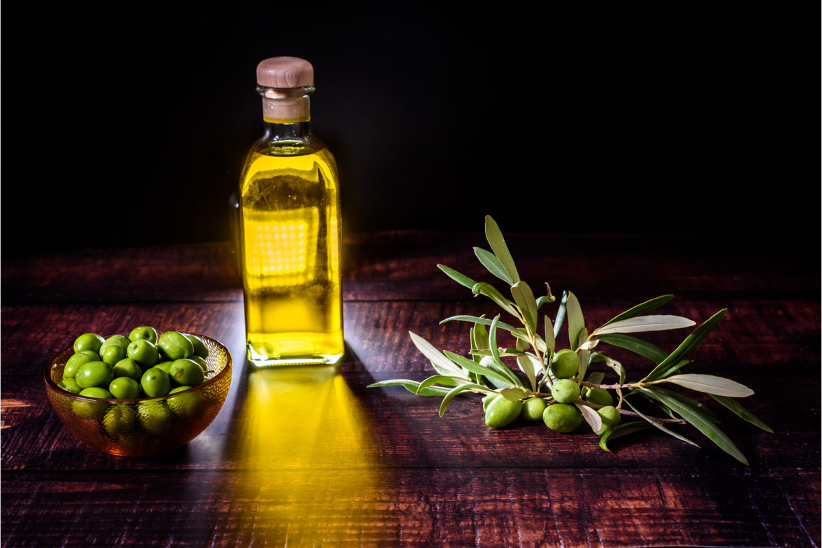 Extrato da oliveira em um recipiente de vidro e oliveira e azeitonas ao lado