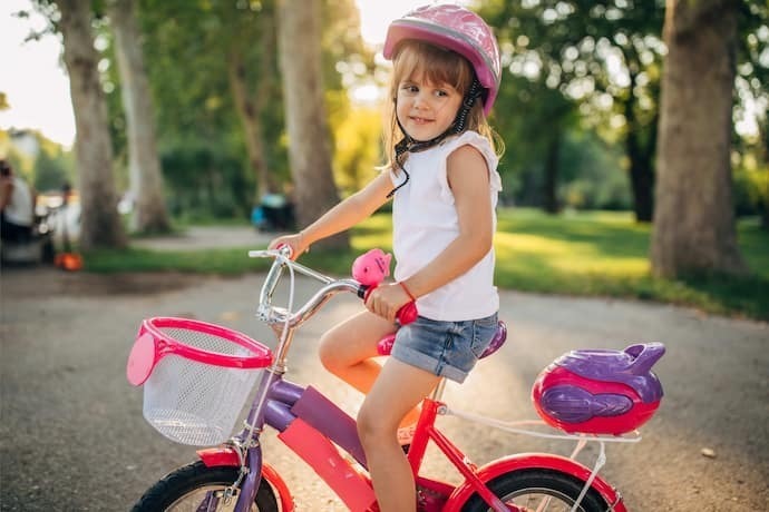 Menina andando de bicicleta colorida com cestinha