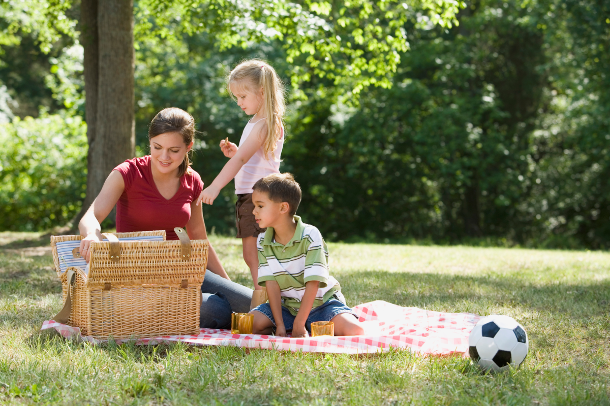 Mãe e filhos fazendo piquenique no parque.