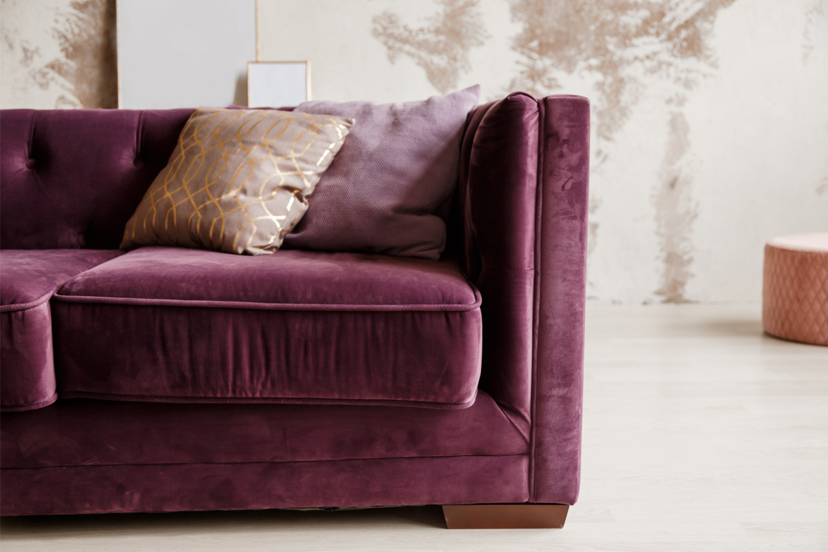 Um sofá de veludo roxo com uma almofada