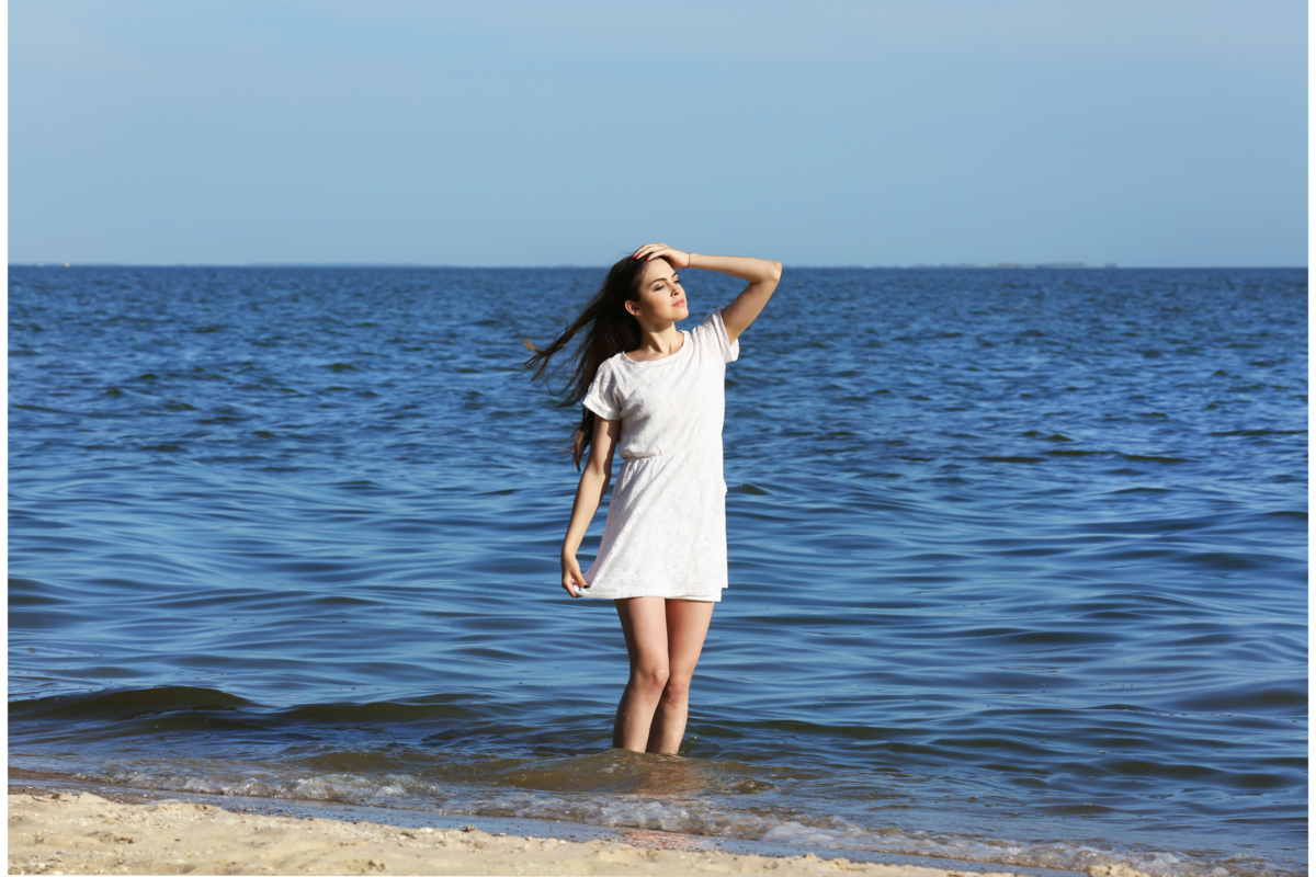 Uma mulher de vestido branco e no mar 