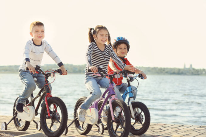 Crianças andando de bicicleta perto de um rio