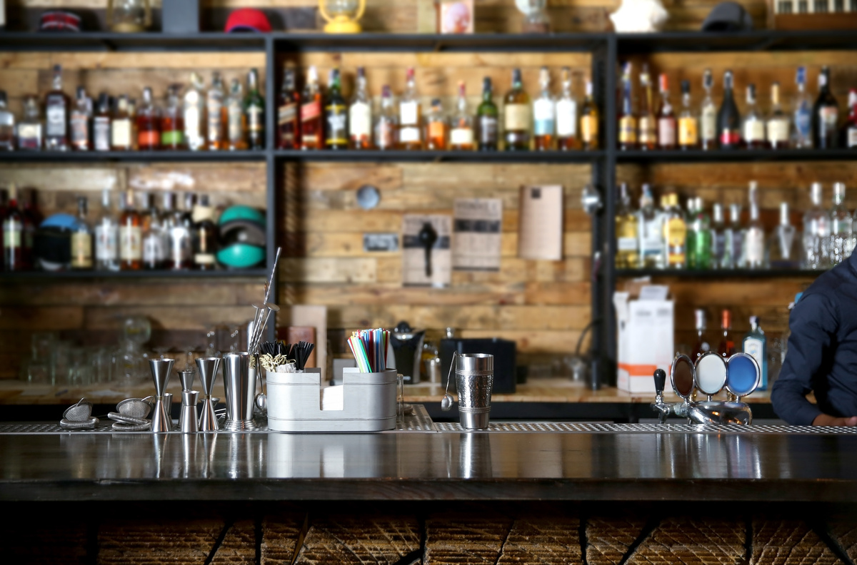 Um bar cheio de garradas de bebidas alcoólicas e uma parede de madeira