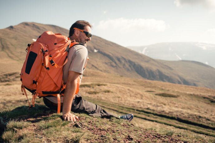 Homem sentado com mochila e olhando para a paisagem