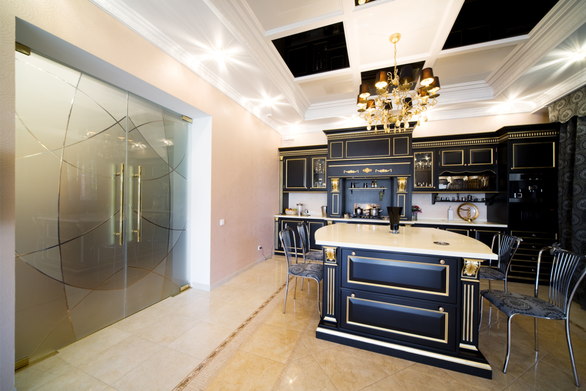 Portas de vidro largas em um cozinha, com móveis pretos e detalhes dourados.