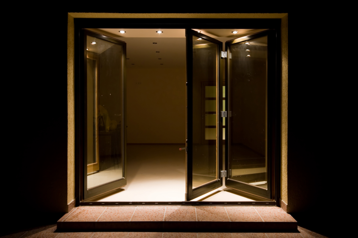 Quatro portas de vidro dobrável com detalhes marrom, em um ambiente espaçoso.